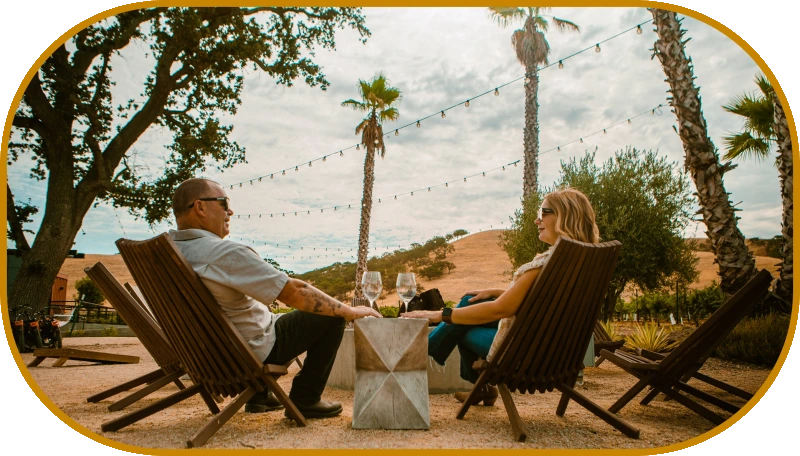 A couple relaxing in chairs under string lights at the winery